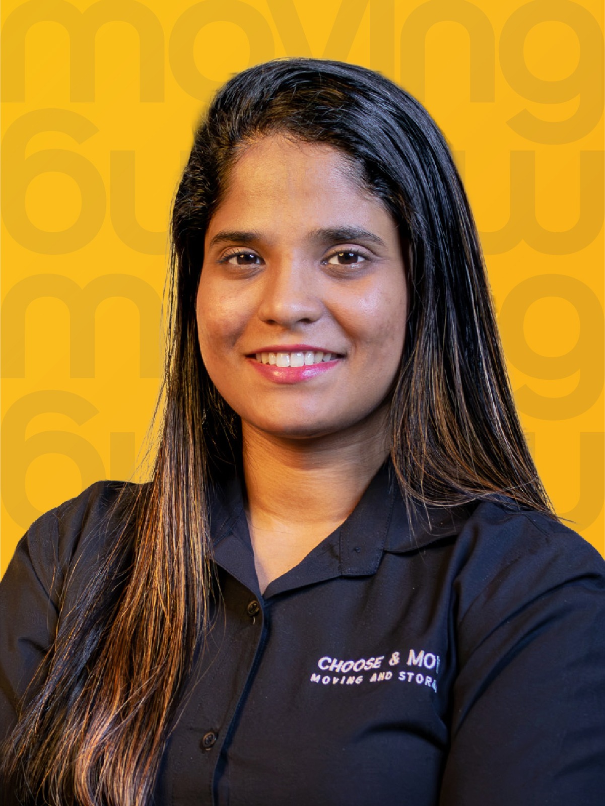 portrait of a smiling woman with long dark hair in a dark shirt, standing in front of a bright yellow patterned background, logo on shirt visible as small text.