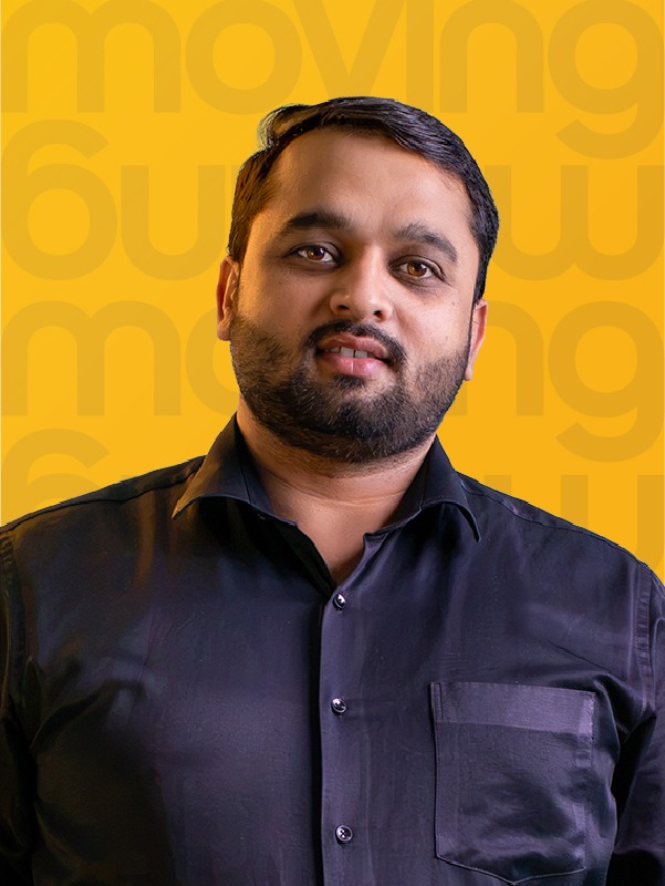 portrait of a man with a beard in a black shirt against a bright yellow background with a repeating 'moving' pattern.